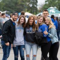 A group of students pose for a photo at a tailgate